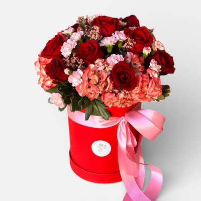 Red roses and pink flowers in a red hat box with a pink ribbon