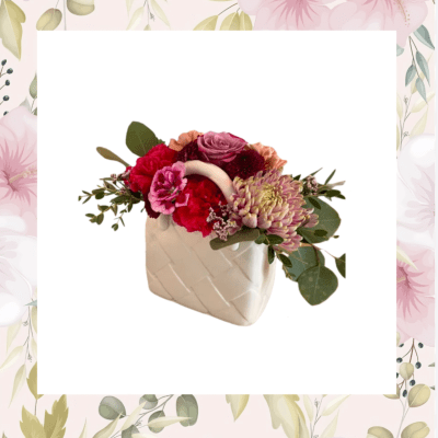 Pink and red flower arrangement in a white ceramic vase
