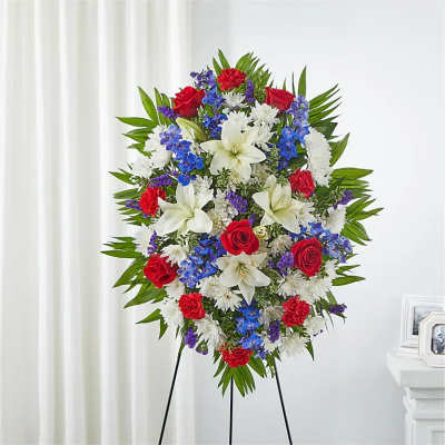 Standing floral spray with red roses, white lilies, and blue flowers