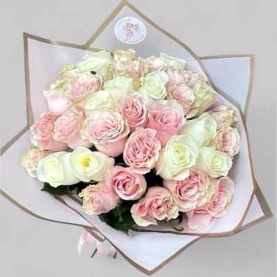 Bouquet of pale pink and white roses wrapped in white paper