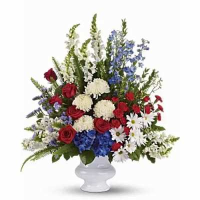 Large red, white, and blue floral arrangement in a white vase