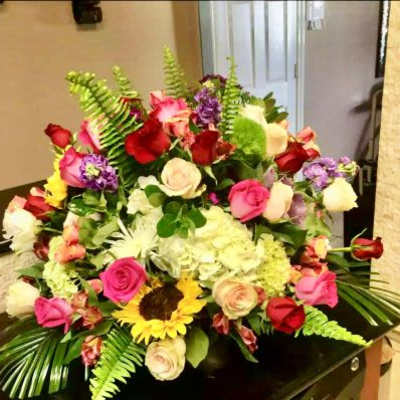 Large mixed arrangement of roses, hydrangea, sunflower and other blooms in a low container