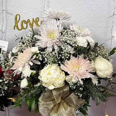 White and blush floral arrangement in a glass vase with a gold bow