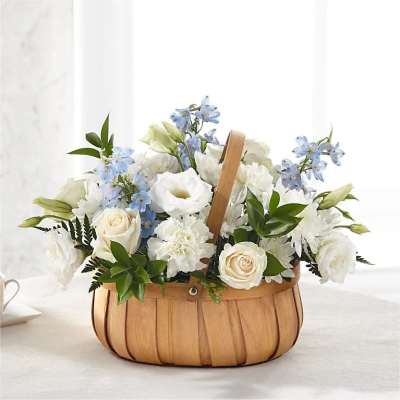 Low wooden basket of white roses, carnations, and blue delphinium in a soft, rounded arrangement