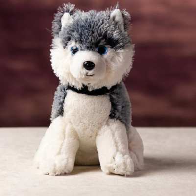Gray and white husky plush toy sitting on a light surface