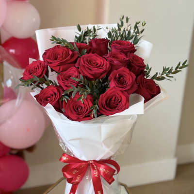 Bouquet of red roses wrapped in white paper with a red ribbon