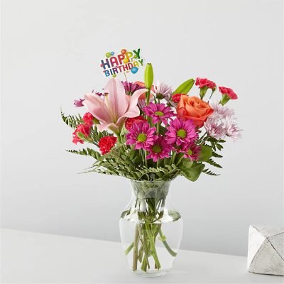 Mixed bouquet in a clear glass vase with a Happy Birthday pick