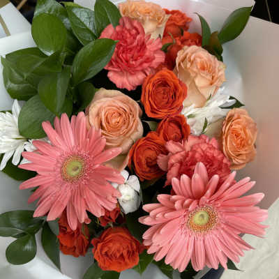 Bouquet of pink gerbera daisies, orange roses, and carnations with white daisies