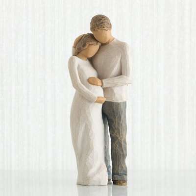 Two carved figurines embracing, one in a white dress and one in gray pants