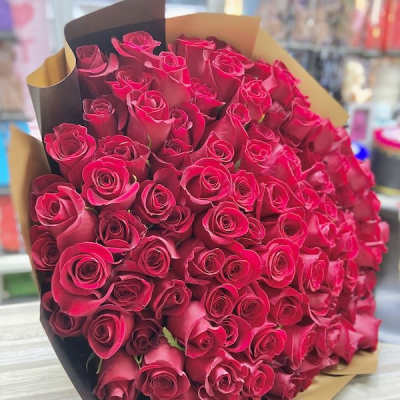 Very large bouquet of red roses wrapped in brown and black paper on a table