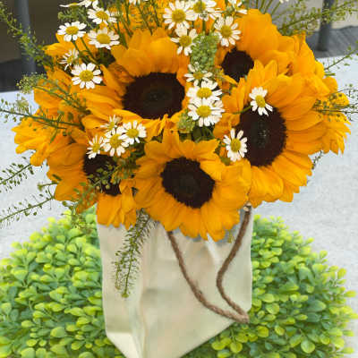 Sunflower bouquet with small white daisies in a white paper bag