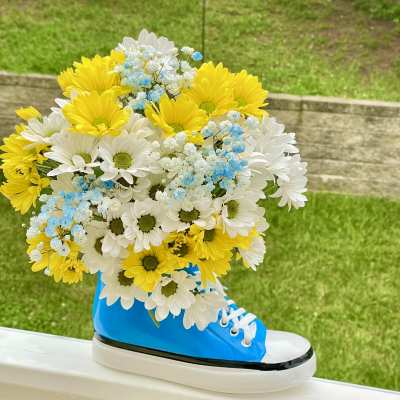 Bouquet of yellow and white daisies with blue baby's breath in a blue sneaker vase