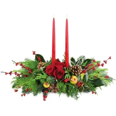 Red roses and candles in a holiday centerpiece with pinecones and berries