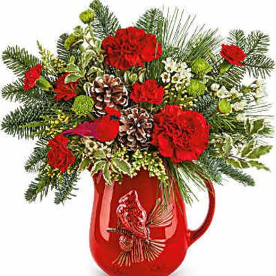 Red carnations and pine in a red holiday pitcher