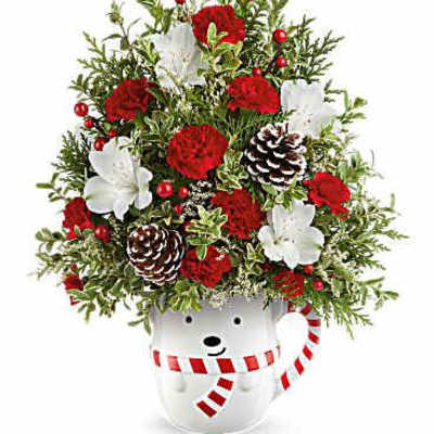Christmas arrangement in a white mug with red flowers and pinecones