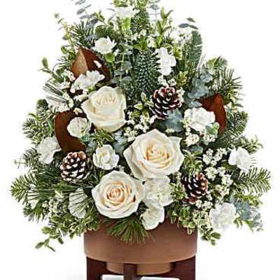 White roses and pinecones arranged in a wooden container
