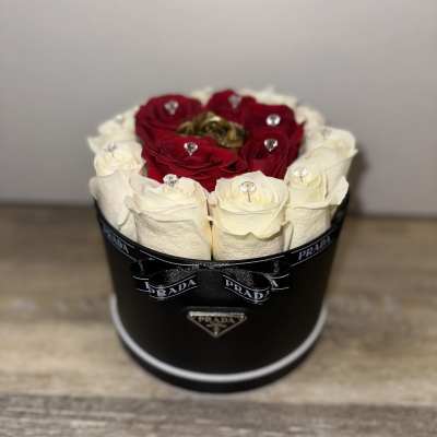 Red and white roses arranged in a black round box with a ribbon