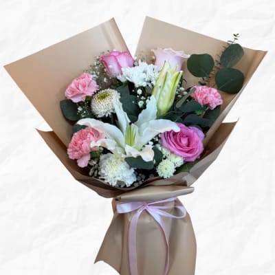 Bouquet of pink and white flowers wrapped in brown paper with a pink ribbon