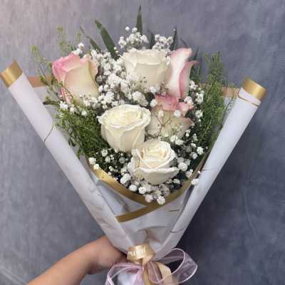 Bouquet of white and pink roses with baby's breath in white wrap