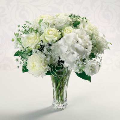 White roses and hydrangeas arranged in a clear glass vase