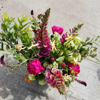 Loose arrangement of bright pink and mixed flowers in a low design on a concrete surface