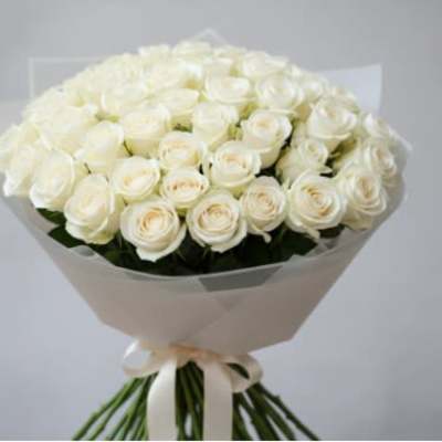 Bouquet of white roses wrapped in pale paper with a ribbon