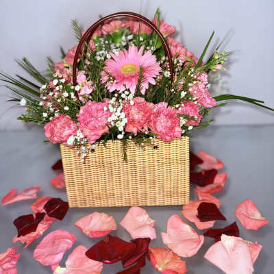 Pink flowers arranged in a wicker basket with a handle