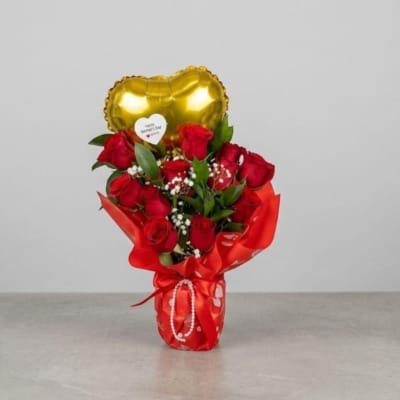 Glass vase wrapped in red paper, natural roses, heart-shaped balloon with a message for Mother's Day