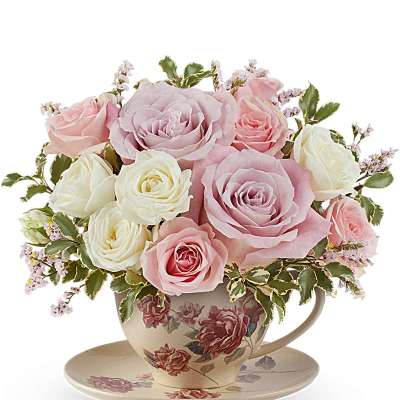 Pink and white roses arranged in a floral teacup with saucer