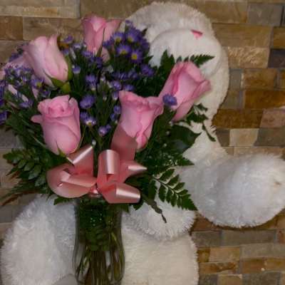 Pink roses and purple daisies in a glass vase with a pink ribbon