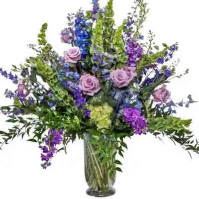 Tall bouquet of purple and blue flowers in a glass vase