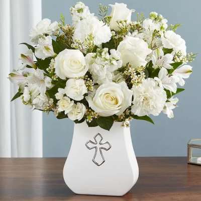 White floral arrangement in a white vase with a cross emblem