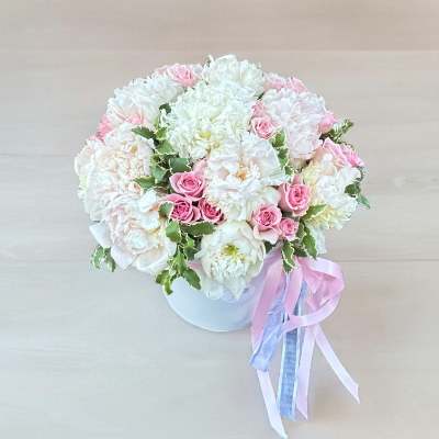 Round bouquet of white and pink flowers in a white box with ribbon tails