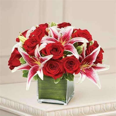 Red roses and pink lilies arranged in a square glass vase
