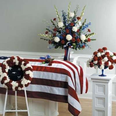 Floral funeral tributes arranged around a flag-draped casket