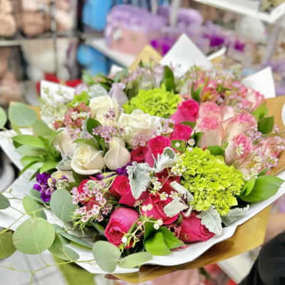 Mixed bouquet of hot pink and ivory roses with lime green blooms in white and gold wrapping