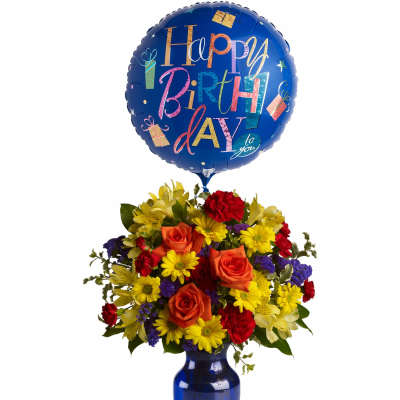 Colorful bouquet of mixed flowers in a blue vase with a large Happy Birthday balloon.