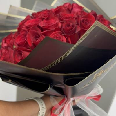 Bouquet of red roses wrapped in black paper with a pink ribbon