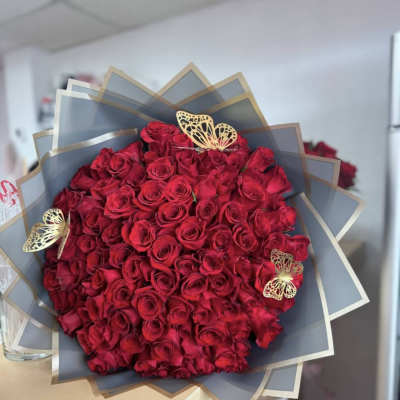 Large bouquet of red roses wrapped in gray paper with gold butterfly accents