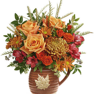 Orange and red floral arrangement in a brown ceramic pitcher with a leaf emblem