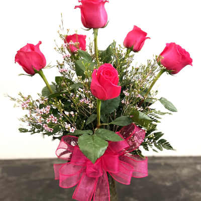 Pink rose bouquet in a glass vase with a pink ribbon bow