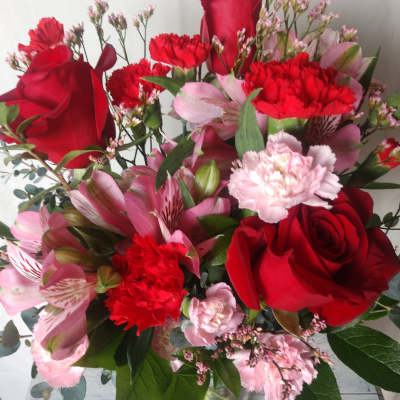 Bouquet of red roses, pink alstroemeria, and carnations in a glass vase