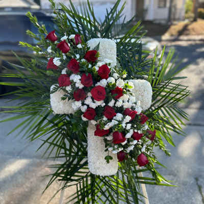 Red roses and white flowers arranged in a cross on an easel