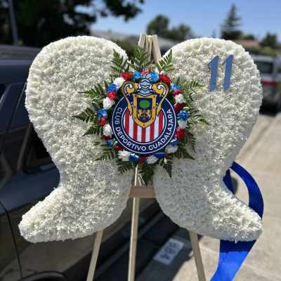 White floral heart wreath on a stand with a sports club emblem