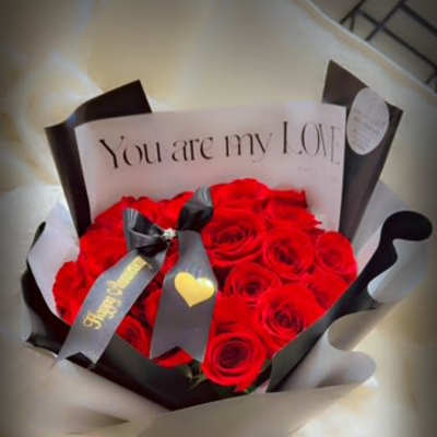 Bouquet of red roses wrapped in black and white paper with a love note