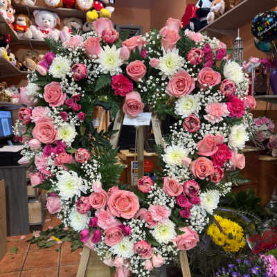 Standing heart-shaped wreath of pink roses and white mums on a wooden easel