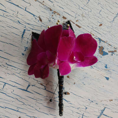 Magenta orchid boutonniere with black ribbon and gold bead accents