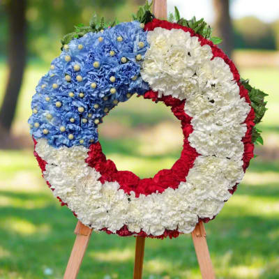 Circular floral wreath in red, white, and blue on a wooden easel