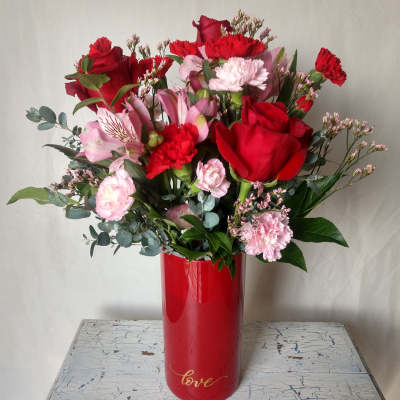Red roses and pink carnations in a red vase