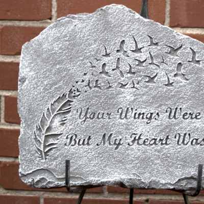 Engraved memorial stone with birds and a feather design